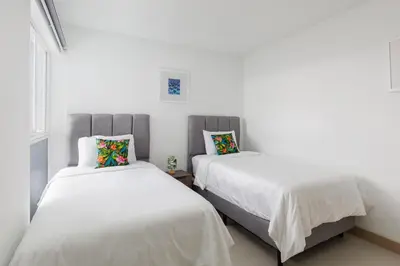 two beds in a room with white walls at Viva Jaco in Jacó