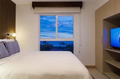 a bedroom with a white bed and a window at Viva Jaco in Jacó