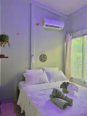 a purple bedroom with a bed with towels on it at Casa mariposa in Uvita
