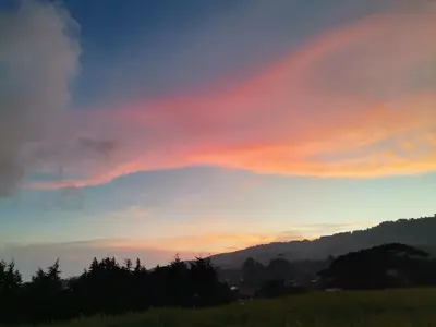 a sunset over a field with trees in the foreground at Monteluna Fraijanes in Poasito