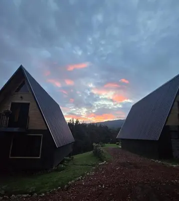 two barns with the sunset in the background at Monteluna Fraijanes in Poasito