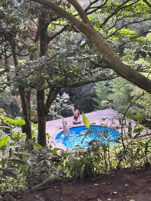 two people sitting in a swimming pool in a garden at Cabaña de Montaña 9per Aire Fresco & Naturaleza in Trojas