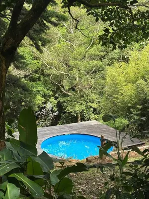 a small blue pond in the middle of a forest at Cabaña de Montaña 9per Aire Fresco & Naturaleza in Trojas