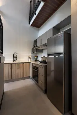 a kitchen with a stainless steel refrigerator and wooden cabinets at Villa Bosque CR in Turrialba