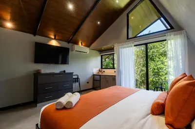 a bedroom with a large bed with a large window at Villa Bosque CR in Turrialba