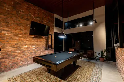 a pool table in a room with a brick wall at Villa Bosque CR in Turrialba