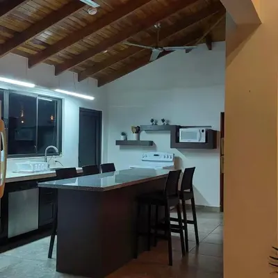 a kitchen with a large island with bar stools at Casa Nosara a 10 minutos de las playas en auto in Nosara