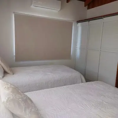 two beds in a small room with white sheets at Casa Nosara a 10 minutos de las playas en auto in Nosara
