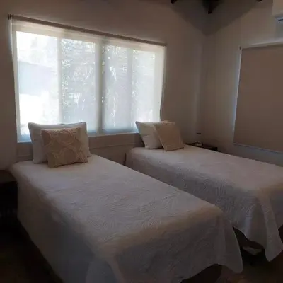two beds in a room with a window at Casa Nosara a 10 minutos de las playas en auto in Nosara