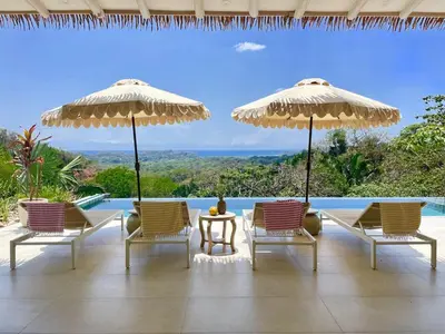 a patio with chairs and umbrellas and a pool at Casa Niri in Nicoya