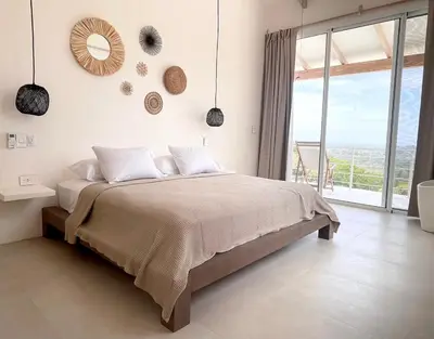 a bedroom with a large bed and a large window at Casa Niri in Nicoya