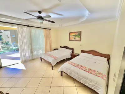 a bedroom with two beds and a ceiling fan at Paradise Beach Apartment Herradura in Herradura