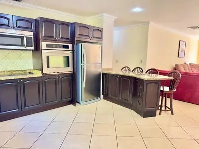 a kitchen with stainless steel appliances and a red couch at Paradise Beach Apartment Herradura in Herradura