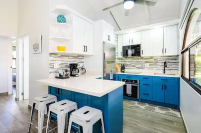 a kitchen with blue cabinets and white counters and stools at Private Patio Villa, Pool Access near Playa Penca in Potrero