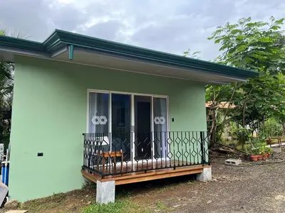 a small green house with a balcony at Villa Binomio in Naranjito