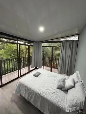 a bedroom with a large bed and large windows at Bromelias in Tambor