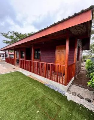 a house with a green lawn in front of it at Cabina Entre Playas in Huacas