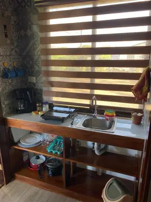 a kitchen with a sink and a window with blinds at Cabina Entre Playas in Huacas