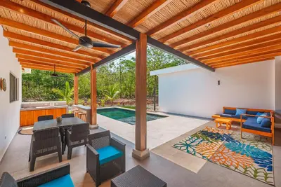 a patio with a table and chairs and a pool at Stylish Private Tropical Escape-10 mins from Tamarindo in Villarreal