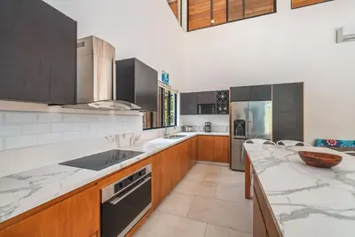a kitchen with marble counter tops and wooden cabinets at Stylish Private Tropical Escape-10 mins from Tamarindo in Villarreal