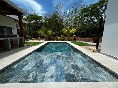 a swimming pool in front of a house at Stylish Private Tropical Escape-10 mins from Tamarindo in Villarreal