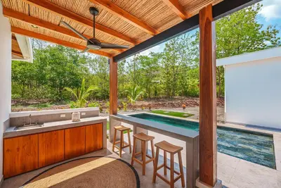 an outdoor bar with stools and a swimming pool at Stylish Private Tropical Escape-10 mins from Tamarindo in Villarreal
