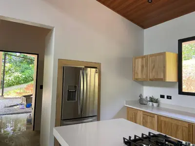 a kitchen with a stainless steel refrigerator and wooden cabinets at La Casa Mokarran in Ojochal