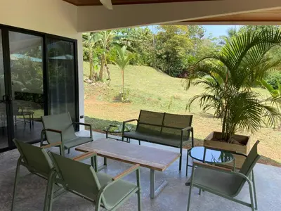 a patio with chairs and a table and a potted plant at La Casa Mokarran in Ojochal