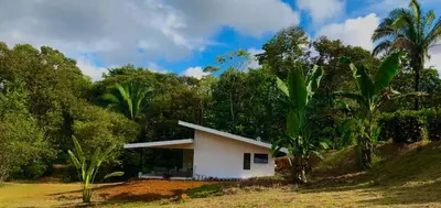 a small white house in the middle of trees at La Casa Mokarran in Ojochal