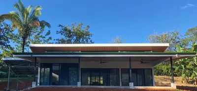 a house with a glass facade with palm trees at La Casa Mokarran in Ojochal