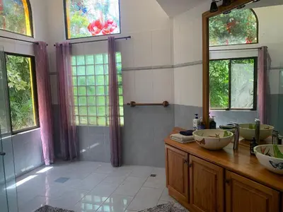 a bathroom with a sink and a shower with windows at Roma del mar - Vila s bazénem a krásným výhledem na moře in Paquera