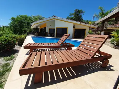 two wooden benches sitting next to a swimming pool at Roma del mar - Vila s bazénem a krásným výhledem na moře in Paquera