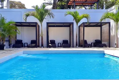 a pool with chairs and palm trees in front of a building at Whitestone Parkview Tamarindo in Tamarindo