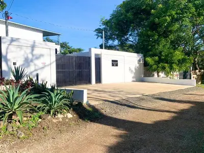 a white building with a gate and a driveway at Whitestone Parkview Tamarindo in Tamarindo