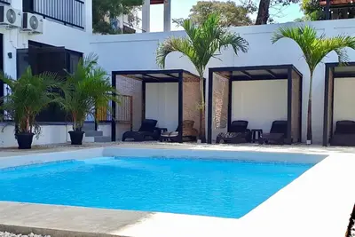a swimming pool in front of a white building with palm trees at Whitestone Parkview Tamarindo in Tamarindo