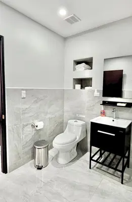 a white bathroom with a toilet and a sink at Whitestone Parkview Tamarindo in Tamarindo