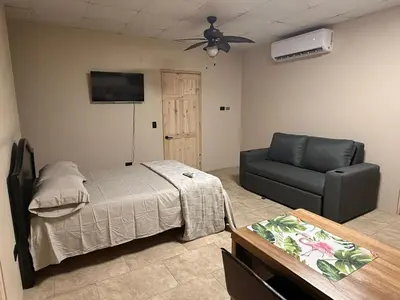 a bedroom with a bed and a couch and a ceiling fan at Apartamentos MarSol in Uvita