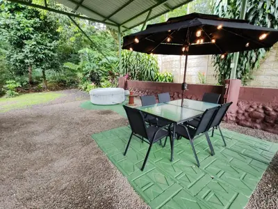 a table and chairs under an umbrella on a patio at Cabaña nido de amor escondida en la naturaleza in San Francisco