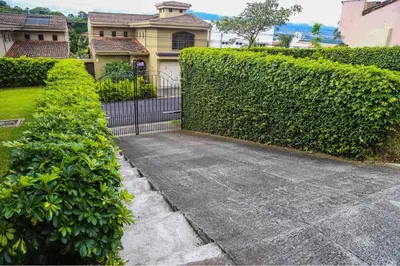 a hedge in front of a house with a driveway at Galeon House in San Rafael