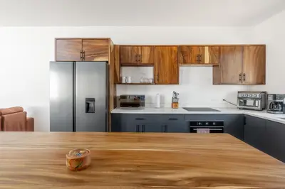 a kitchen with wooden cabinets and a wooden table at Casa Aurora with Private Patio & Pool in Coco