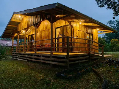 a wooden cabin with a porch and lights on it at Santa Maria Volcano Lodge Hotel & Restaurante in Hacienda Santa María
