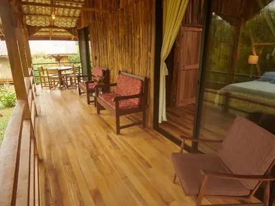 a porch of a house with chairs and a bed at Santa Maria Volcano Lodge Hotel & Restaurante in Hacienda Santa María