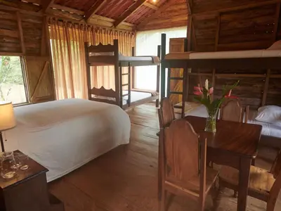 a bedroom with a bed and a desk and a bed and bunk beds at Santa Maria Volcano Lodge Hotel & Restaurante in Hacienda Santa María