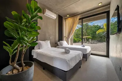 a bedroom with two beds and a potted plant at Nelblu Flamingo Suites in Playa Flamingo