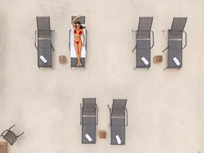 an overhead view of a woman in a surfboard next to chairs at Nelblu Flamingo Suites in Playa Flamingo