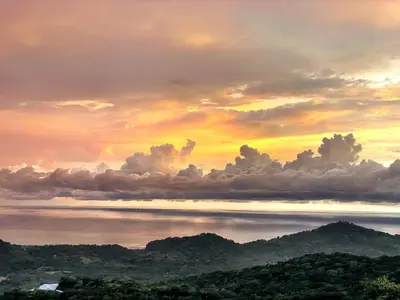 a sunset over the water with mountains and clouds at Villa Cielo Sueños in Carrillo