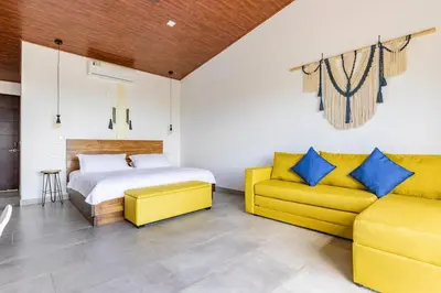 a bedroom with a bed and a yellow couch at Casa Coroico Infinity Pool BBQ Sunset Views in Santa Cruz