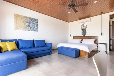 a bedroom with a bed and a blue couch at Casa Coroico Infinity Pool BBQ Sunset Views in Santa Cruz
