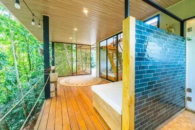 a house with a blue brick wall and a wooden deck at New, Private River, Wifi, AC, King Bed, Jungle Shower in Ojochal
