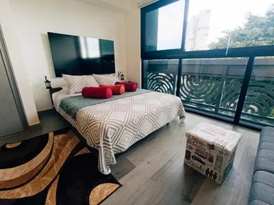 a bedroom with a bed and a large window at Lovely comfy studio in the city, with AC in San José